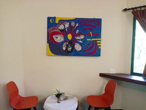 une table et deux chaises ainsi qu'un tableau sur le mur dans l'établissement Smiley Resorts, à Auroville