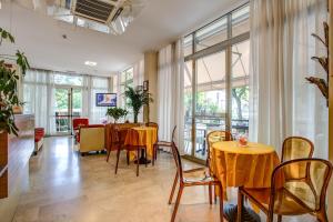 a dining room with tables and chairs and windows at Hotel Tiziana in Rimini