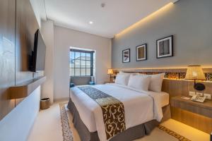 庫塔的住宿－MONTANA @OCEANSIDE MANDALIKA，一间酒店客房,配有一张床和一台电视
