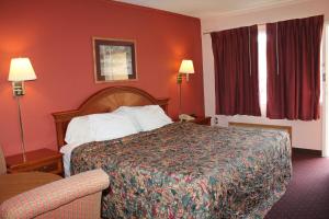 Andrew Johnson Inn في Greeneville: غرفة فندق بسرير وجدران حمراء
