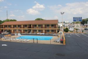 a hotel with a swimming pool in front of a parking lot at Andrew Johnson Inn in Greeneville
