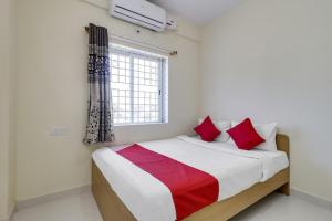 een slaapkamer met een bed met rode kussens en een raam bij Anjana residency in Bangalore