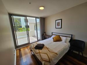 a bedroom with a bed and a chair and a window at Spacious Modern Apartment in Prime Location in Wickham