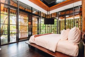 una camera con un letto in una stanza con finestre di The Sense Resort Kanchanaburi a Kanchanaburi