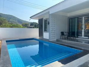 a swimming pool in front of a house at Tai Chon Pool Villa ใต้ชล พูลวิลล่า in Ban Khlot