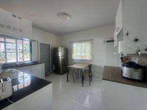 a kitchen with a table and a refrigerator at Tai Chon Pool Villa ใต้ชล พูลวิลล่า in Ban Khlot