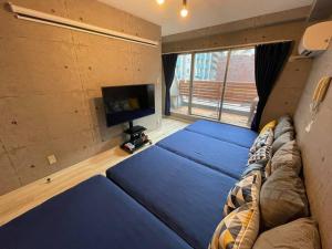een woonkamer met een blauwe bank en een tv bij TasoneUrbanStayOsaka 心斎橋東アクエルド502 in Osaka