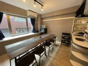 een keuken met een lange tafel en stoelen in een kamer bij TasoneUrbanStayOsaka 心斎橋東アクエルド502 in Osaka
