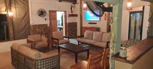 a living room with couches and chairs and a television at Mazunga Tented Camp in Gravelotte