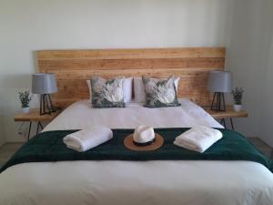 a bed with a hat and two towels on it at Vischgat farm guest house in Loxton