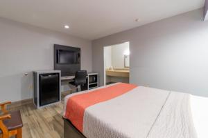 Dormitorio con cama, escritorio y TV en Holiday Terrace Motel, en Houston