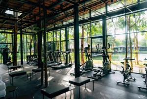 un gimnasio con filas de cintas de correr y máquinas elípticas en The Sense Resort Kanchanaburi en Kanchanaburi