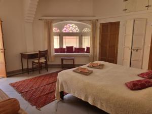 a bedroom with a bed and a table and a window at Apani Dhani Eco-Lodge in Nawalgarh