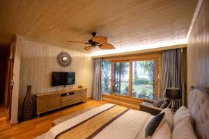 - une chambre avec un lit, une télévision et un canapé dans l'établissement 4br Villa River Deck, Pool, Bbq & Garden, à Thuan An