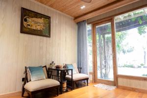 Habitación con 2 sillas, mesa y ventana en 4br Villa River Deck, Pool, Bbq & Garden, en Thuan An