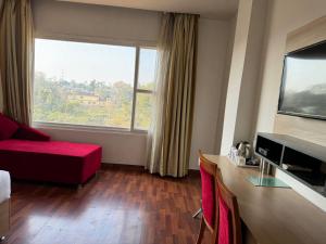 une chambre d'hôtel avec un canapé rouge et une grande fenêtre dans l'établissement Hotel River Retreat, à Kangra