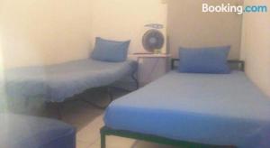 two beds in a room with blue sheets at Kos Omah Yanto 19 in Jakarta