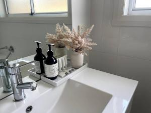 a bathroom sink with two bottles of soap and flowers at Stylish Open Plan Retreat in Wagga Wagga +8 photos