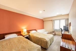 a hotel room with two beds and a television at HOTEL NEWITAYA in Utsunomiya