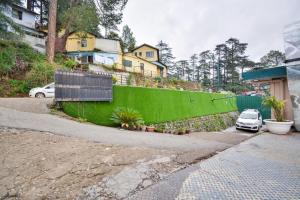 un coche aparcado frente a una pared verde en Aangan regency en Shimla