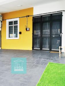 a yellow building with black doors and a yard at HYDA Homestay Melaka, Durian Tunggal in Kampong Tengah