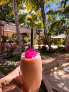 a person holding a pink drink with a pink flower at Cabana Capybara in Mirissa