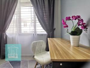 a dining room table with a vase of flowers on it at HYDA Homestay Melaka, Durian Tunggal in Kampong Tengah