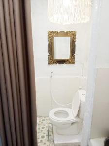 bagno con servizi igienici bianchi e specchio di Local House Grenceng 2 a Denpasar