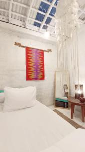 una camera con un letto bianco e un dipinto sul muro di Local House Grenceng 2 a Denpasar
