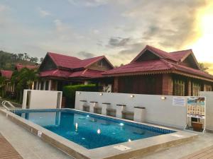 a swimming pool in front of a house at Jasmine Villa in Pantai Cenang