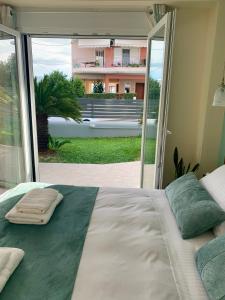 a bedroom with a large bed with a large window at Modern mint sunny house near the airport in Spata