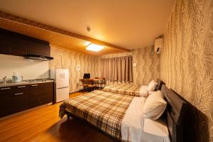 um quarto de hotel com duas camas e uma cozinha em BEPPU HOSTEL U&T em Beppu