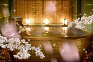 uma banheira com velas num quarto com flores em THE JUNEI HOTEL Kyoto Imperial Palace West em Quioto