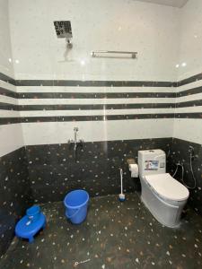 a bathroom with a toilet and a blue bucket at The Rare Ones - Resorts, Cafe & Game Zone in Mukteshwar