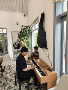2 personnes assises au piano dans une pièce dans l'établissement Tia Du Homestay, à Đà Lạt