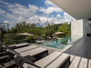 ein Pool mit Stühlen und Sonnenschirmen auf einem Gebäude in der Unterkunft Malaiwana Residences in Nai Thon Beach