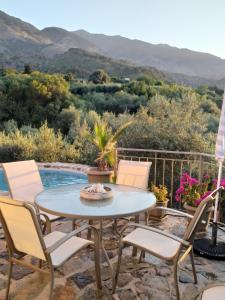 un patio con mesa, sillas y piscina en "Villa Kastania" Melidoni, Crete, en Melidhónion
