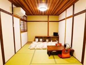 a room with a bed and a table in it at Guest House Nakamura in Ama