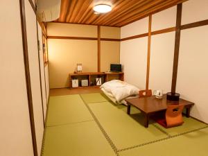 a room with a table and a bed in it at Guest House Nakamura in Ama