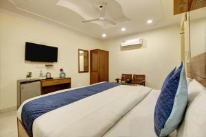 een slaapkamer met een groot bed en een flatscreen-tv bij Hotel The Eden Park in Noida