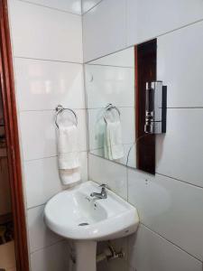 a white bathroom with a sink and a mirror at R&M APARTMENTS in Nairobi