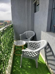 2 chaises et une table sur un balcon dans l'établissement R&M APARTMENTS, à Nairobi