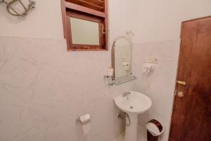 Baño blanco con lavabo y espejo en Muhsin Villa - Galle Fort en Galle