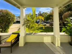 un porche con un banco amarillo y una palmera en Glendale House en Glendale