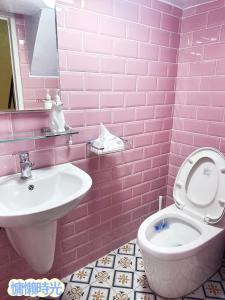 Baño de color rosa con aseo y lavamanos en Lazy Time B&B, en Miaoli