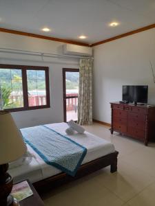 Schlafzimmer mit einem Bett, einem TV und Fenstern in der Unterkunft Bayview Villa -Sea Side Villa in Mahé