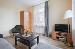 sala de estar con sofá, TV y mesa en Kauko Laiptu Apartamentai, en Kaunas