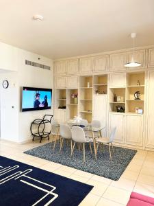 Charming spacious studio apartment in the heart of JBR By SWEET HOMES في دبي: غرفة معيشة مع طاولة وكراسي وتلفزيون