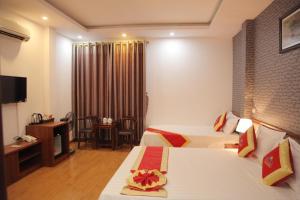 a hotel room with two beds and a television at Khách sạn Bảo Sơn 1 in Lao Cai