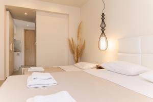 um quarto branco com duas camas com toalhas em Mystery Suites and Apartments em Neoi Poroi